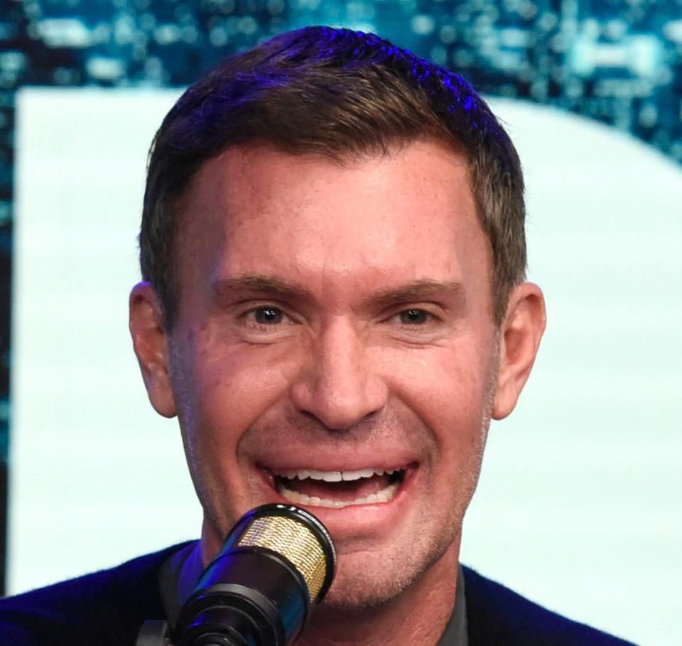 Jeff Lewis seated at a table speaking into a microphone, surrounded by Christmas-themed decorations