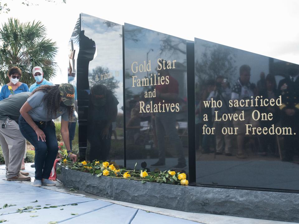 Gold Star Family members place yellow roses at the base of the new Gold Star Families Memorial Monument during the Veterans Day Observance at Veterans Memorial Park in downtown Pensacola on Wednesday, Nov. 11, 2020.