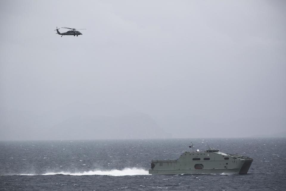 In this Tuesday, March 21, 2017 photograph, an Omani naval vessel sails alongside the USS George H.W. Bush as it travels through the Strait of Hormuz. The arrival of the nuclear-powered aircraft carrier to the Persian Gulf marks the first such deployment under new U.S. President Donald Trump. (AP Photo/Jon Gambrell)