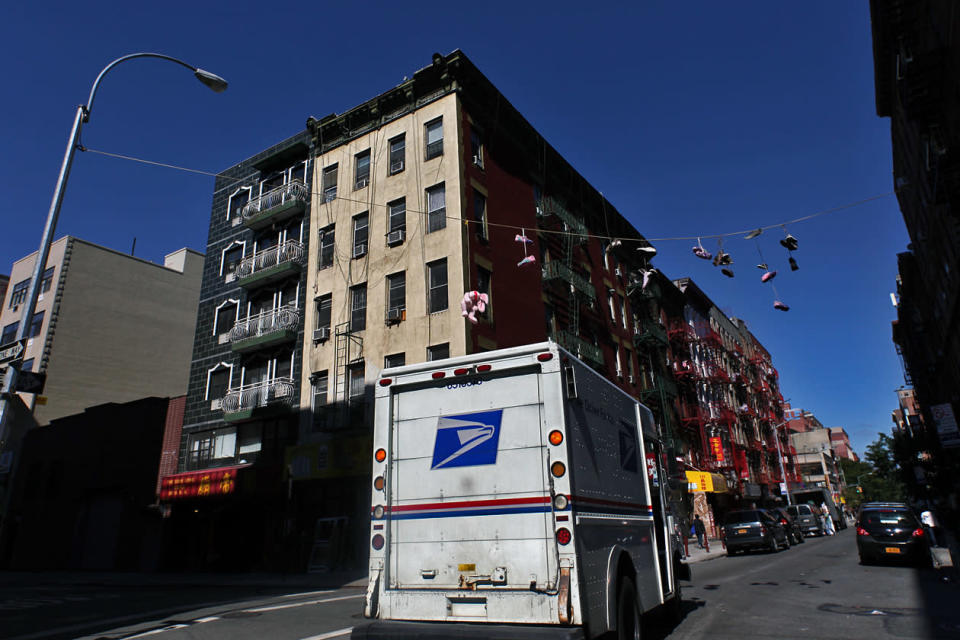 A United States Postal Services mail truck driving past orchard street in the Chinatown neighborhood in Manhattan, New York City.