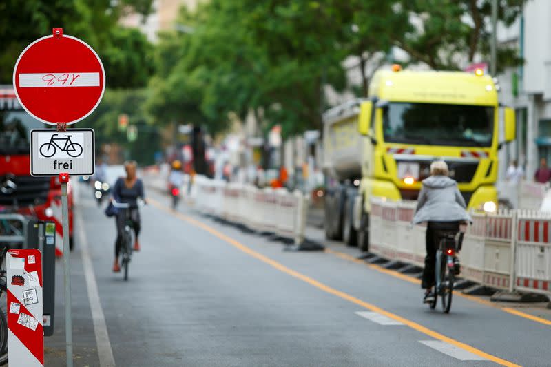 People ride on bicycles as workers build bicycle lanes, in Berlin