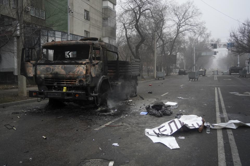 FILE - A body of victim covered by a banner, right, lays near to a military truck, which was burned after clashes, in Almaty, Kazakhstan, Thursday, Jan. 6, 2022. The government, by then led by Nazarbayev's close ally Tokayev, responded with a deadly clampdown, culminating in a "shoot-to-kill" order as the president blamed "terrorists" allegedly funded and trained from abroad. (Vladimir Tretyakov/NUR.KZ via AP, File)