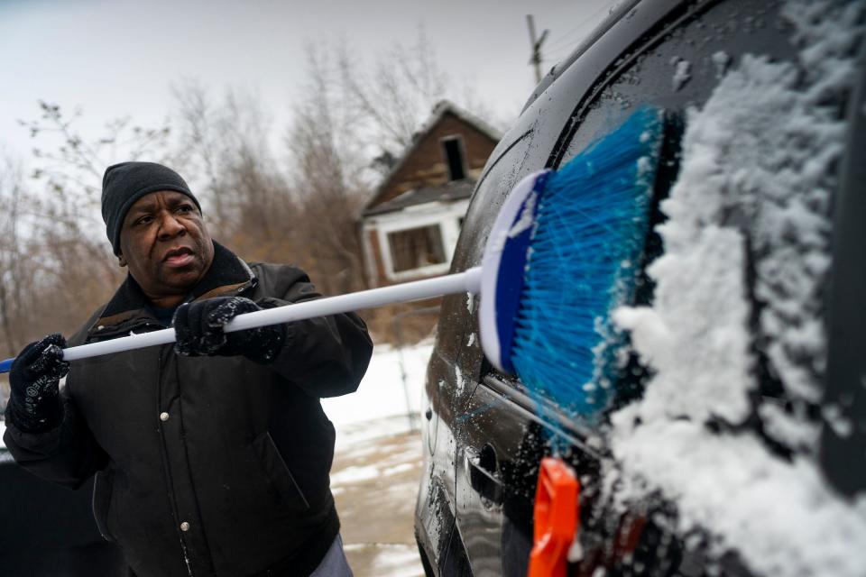 Jimmy Parker cleans snow off his car at his home on Sunday, Jan. 31, 2021, in Detroit. "I like the fresh air. It's quiet. No one's around," he said.