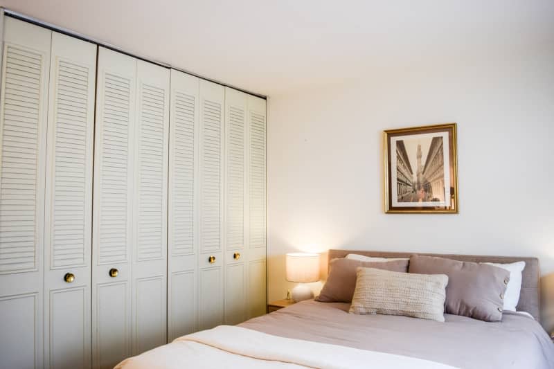 Built-in closet next to bed with decorative pillows  and framed artwork