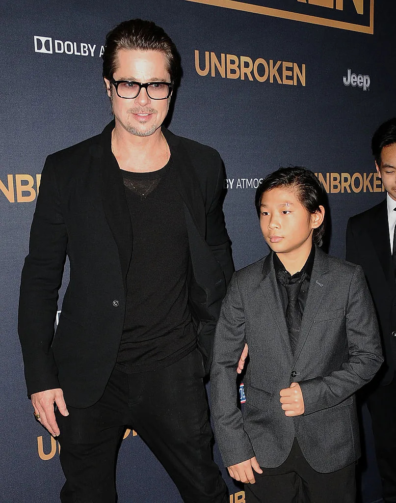 Brad Pitt in a black suit and glasses with Maddox Jolie-Pitt in a suit at the 'Unbroken' premiere