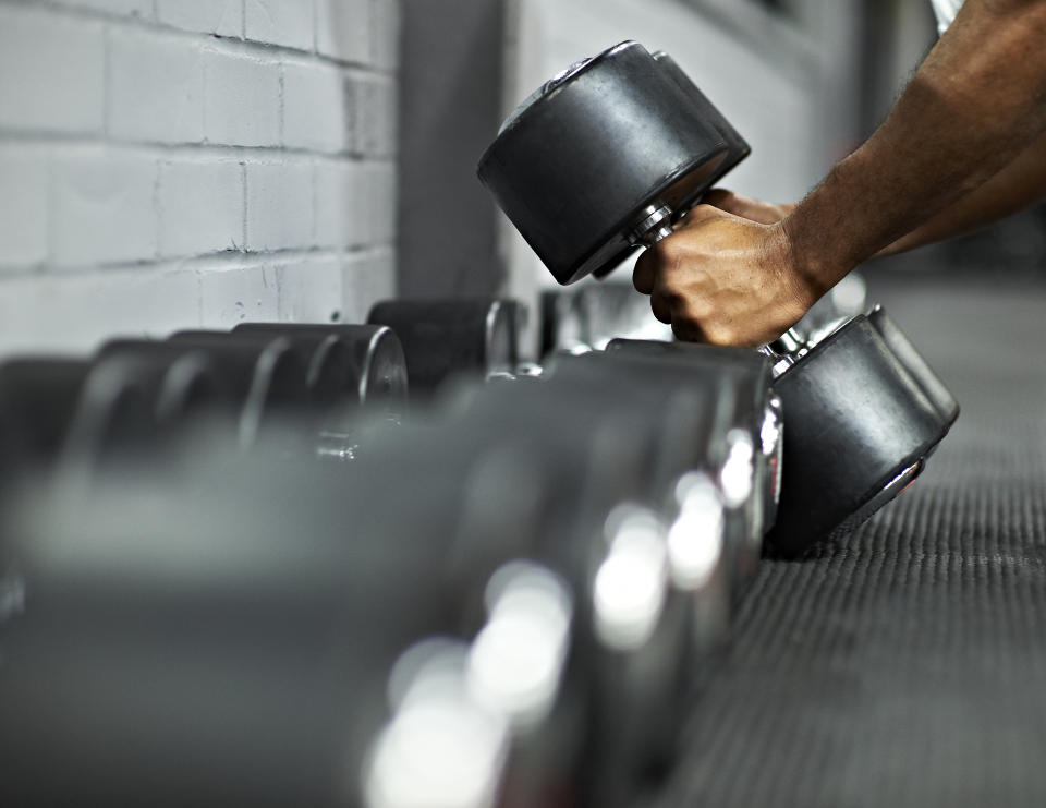 Male picking up dumbbells from selection of free weights in gym, ready for workout
