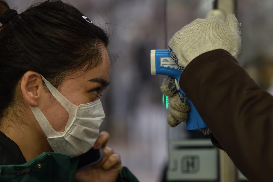 A worker checks the temperature of a customer at the entrance of a supermarket in Shanghai on February 26, 2020. - China on February 26 reported 52 new COVID-19 coronavirus deaths, the lowest figure in more than three weeks, bringing the death toll to 2,715. (Photo by Hector RETAMAL / AFP) (Photo by HECTOR RETAMAL/AFP via Getty Images)