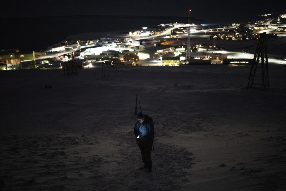 El miembro de Svalbard Kirke, Lars-Olav Tunheim, revisa su teléfono mientras sube la montaña Plataberget al mediodía en Longyearbyen, Noruega, el miércoles 11 de enero de 2023. (AP Foto/Daniel Cole)
