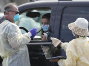 People wait inside their vehicles in line at a mass COVID-19 vaccination site outside The Forum in Inglewood, Calif., Tuesday, Jan. 19, 2021. (AP Photo/Damian Dovarganes)