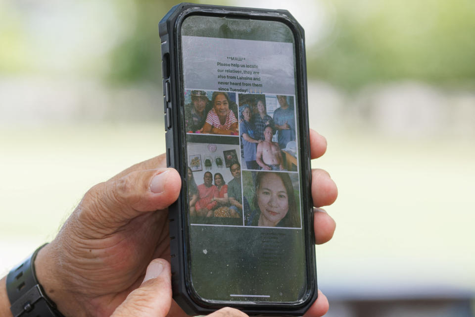 A phone showing images of people who are missing after wildfires on Maui, Hawaii.