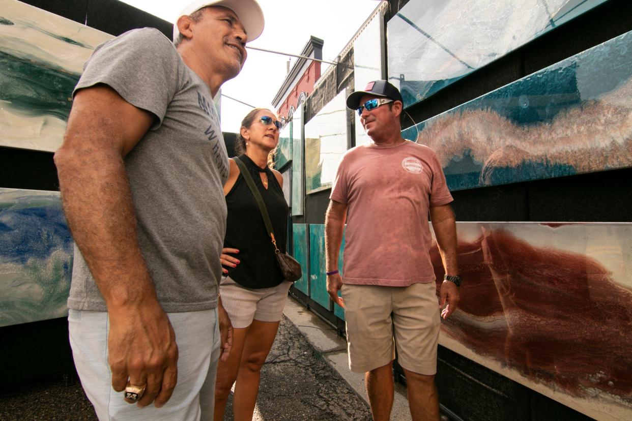 Mike and Marcy Amine of Brighton, left, admire the resin fusion art of Robert Lowe, right, at the Brighton Art and Music Festival Friday, Aug. 5, 2022.