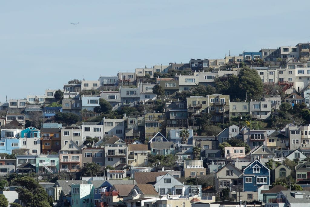 A plane flies over homes and residential buildings in San Francisco, Wednesday, March 4, 2020. California lawmakers have reached a deal on a pair of housing production bills. (AP Photo/Jeff Chiu, File )