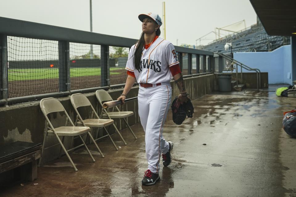 Kelsie Whitmore, a 23-year-old two-way player for the Atlantic League's Staten Island FerryHawks, visits the dugout before gametime, Friday, May 13, 2022, in New York. Whitmore is one of the first women to be in the starting lineup and pitch relief with a professional team connected to Major League Baseball. (AP Photo/Bebeto Matthews)