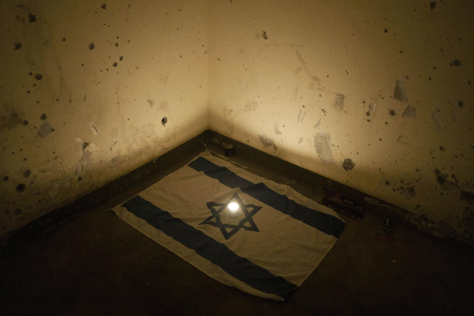 A candle is placed over an Israeli national flag inside a roadside bomb shelter where people were killed during the Hamas militants attack near the Israeli-Gaza border in Israel, Saturday, Jan. 6, 2024. At least, 1,200 people were killed in the Oct. 7 attack, which triggered the latest Israel-Hamas war, (AP Photo/Leo Correa)