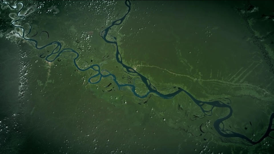 A view of an incredibly long river flowing through a forested area as seen from space.