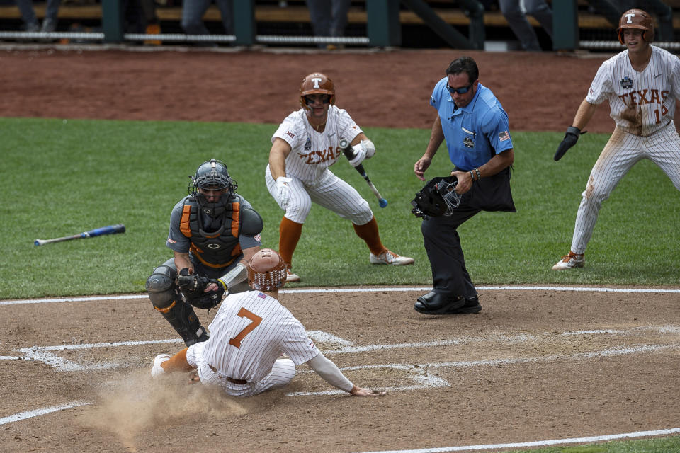 Texas outfielder Douglas Hodo (7) slides into home against Tennessee catcher Connor Pavolony (17) to score in the fourth inning of an NCAA college baseball game in the College World Series Tuesday, June 22, 2021, at TD Ameritrade Park in Omaha, Neb. (AP Photo/John Peterson)