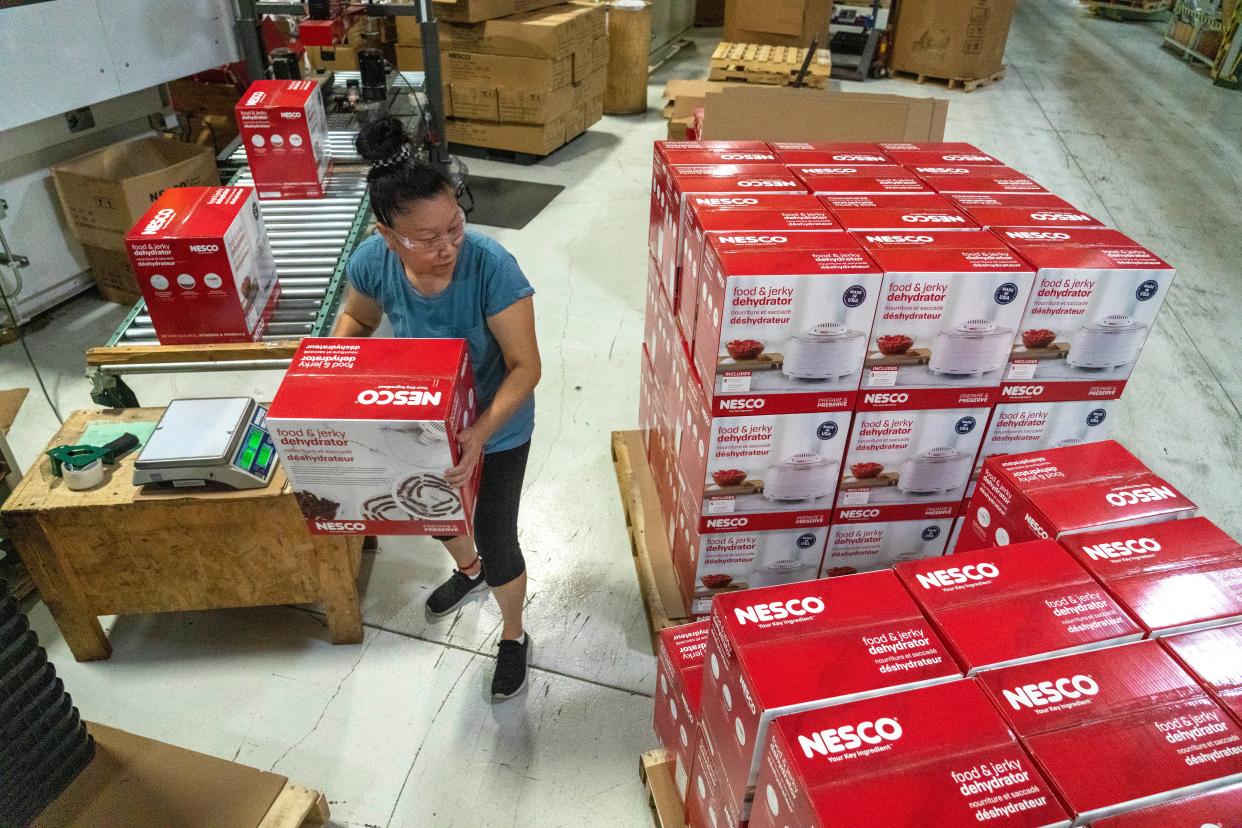 Injection press operator Yang Xiong stacks NESCO food and jerky dehydrators Tuesday, August 23, 2022 at The Metal Ware Corp. in Two Rivers, Wis. The appliance uses electrical parts made in China that are assembled and mated with parts made in Two Rivers. The privately held company, which became famous for its NESCO roasters that are now made in China, has been shifting some manufacturing of other products back to the city on Lake Michigan.