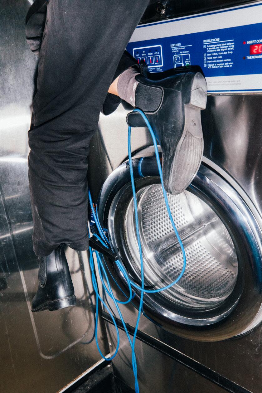 A person's feet in front of a laundromat washing machine