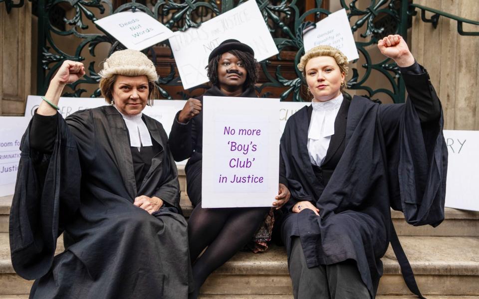 Female lawyers hold placards on the steps of the Garrick Club