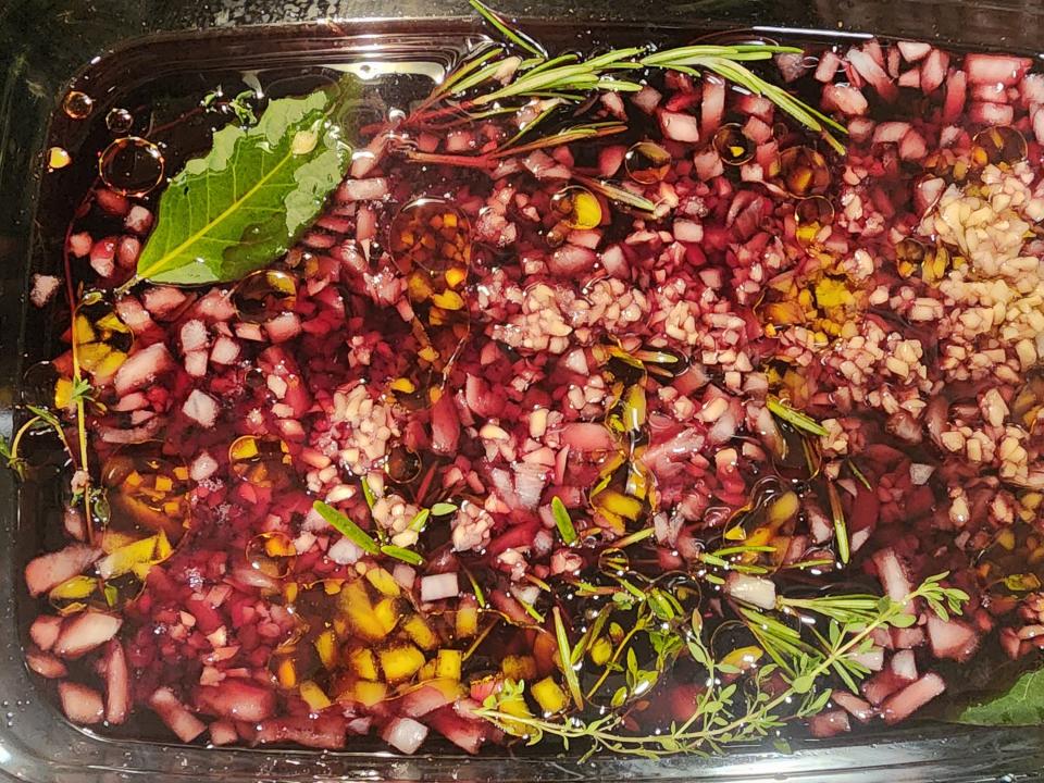 Pink marinade with herbs and oil in a glass dish