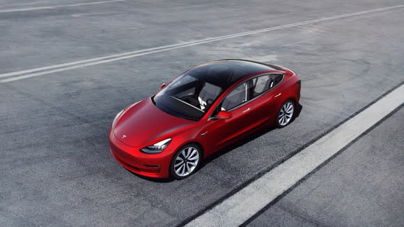 A red Model 3 on gray pavement