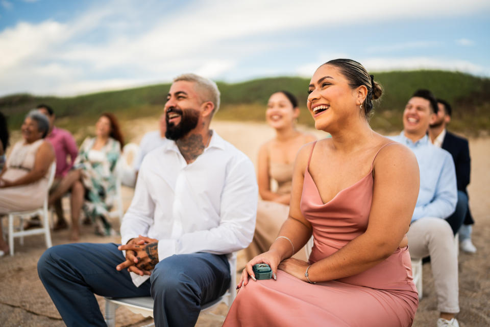 Wedding guests laughing during wedding ceremony on the beach.