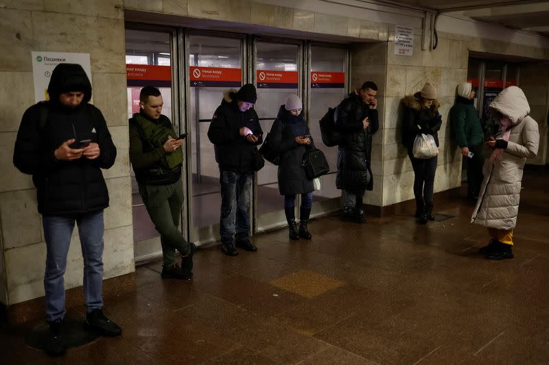 People use mobile internet next to a metro station after critical civil infrastructure was hit by Russian missile attacks in Kyiv