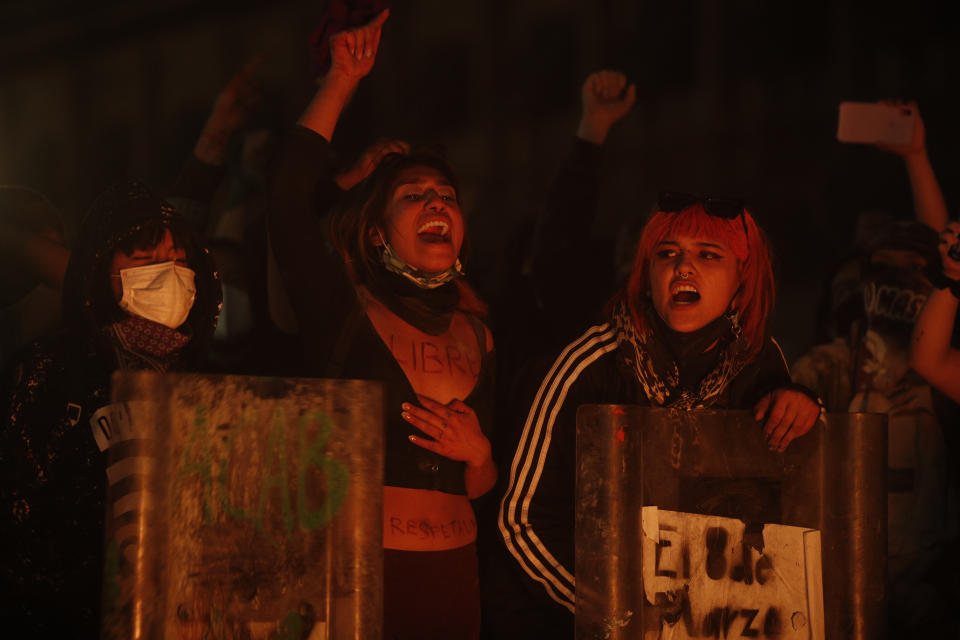 Women demonstrators chant slogans as they hold shields they ripped away from police officers hands in clashes in front of the National Palace during a march to commemorate International Women's Day and protesting against gender violence, in Mexico City, Monday, March 8, 2021. (AP Photo/Rebecca Blackwell)