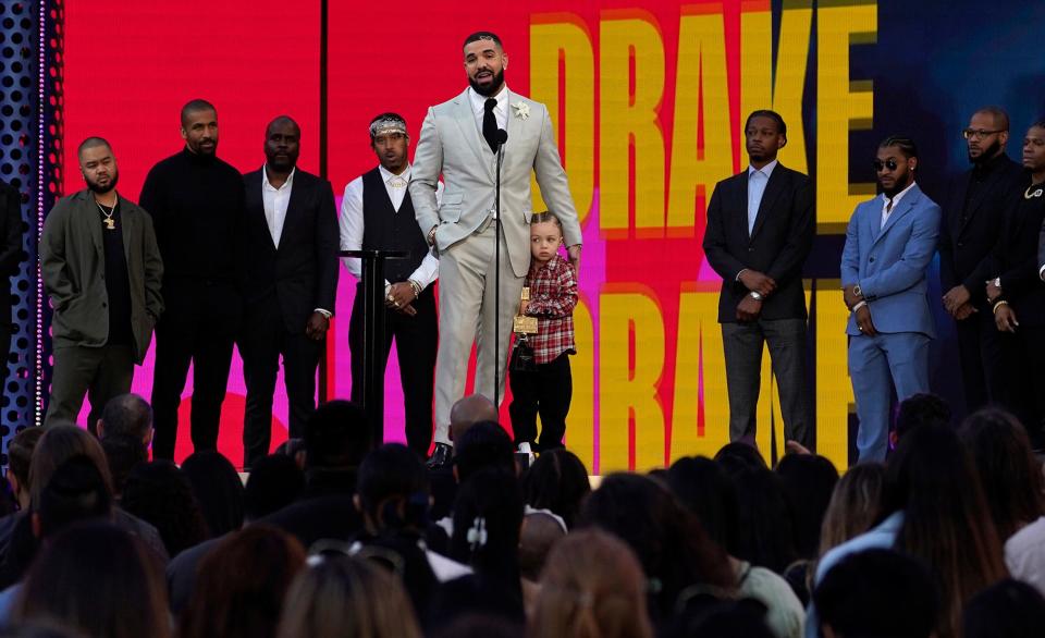 Friends and family look on as Drake accepts the artist of the decade award while he holds his son Adonis Graham.