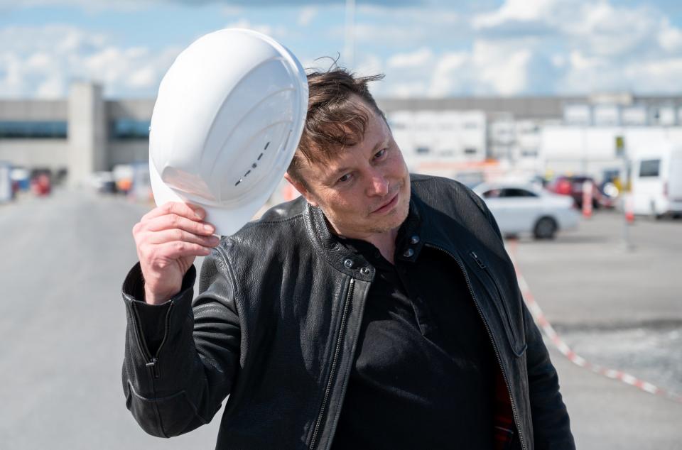 Elon Mush holds a Tesla-branded hard hat.