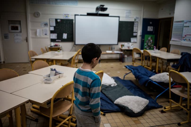 A child prepares to sleep in a classroom on January 10, 2018 in Vaulx-en-Velin, near Lyon, central-eastern France, as teachers and parents of pupils welcome homeless families