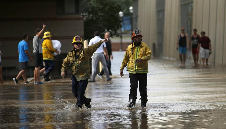 Firefighters shout directions as they wade through water near Pauley Pavillion on the University of California, Los Angeles campus, which is flooded after a broken 30-inch water main gushed water onto Sunset Boulevard, in the Westwood section of Los Angeles July 29, 2014. The geyser from the 100-year-old water main flooded parts of the UCLA campus and stranded motorists on surrounding streets. REUTERS/Danny Moloshok