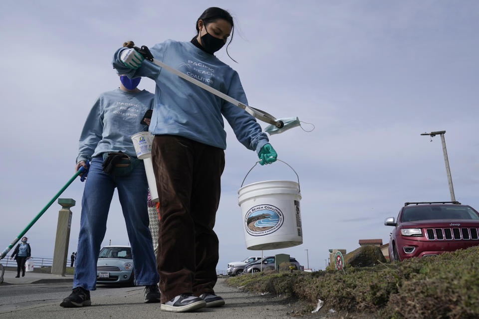 La voluntaria Amaelia Bringas, de 16 años, recoge un tapabocas durante tareas de limpiza de la playa de Pacifica, California, el 17 de marzo del 2021. (AP Photo/Jeff Chiu)