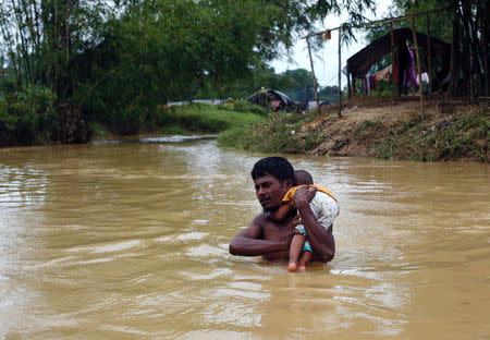 A Rohingya refugee carries a baby through a swollen water stream in Cox's Bazar, Bangladesh September 18, 2017. REUTERS/Danish Siddiqui