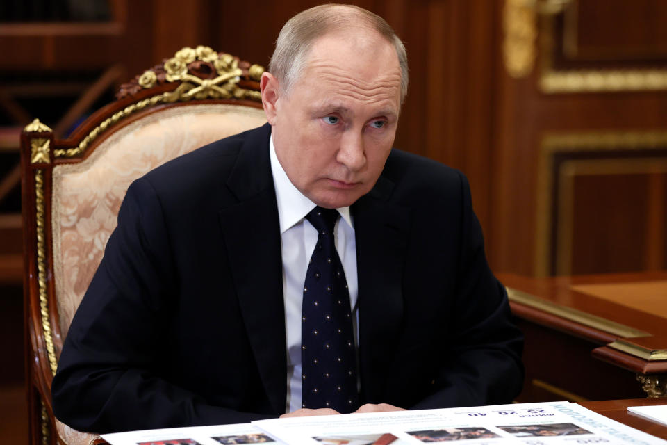 Russian President Vladimir Putin sits at a desk during a meeting. 