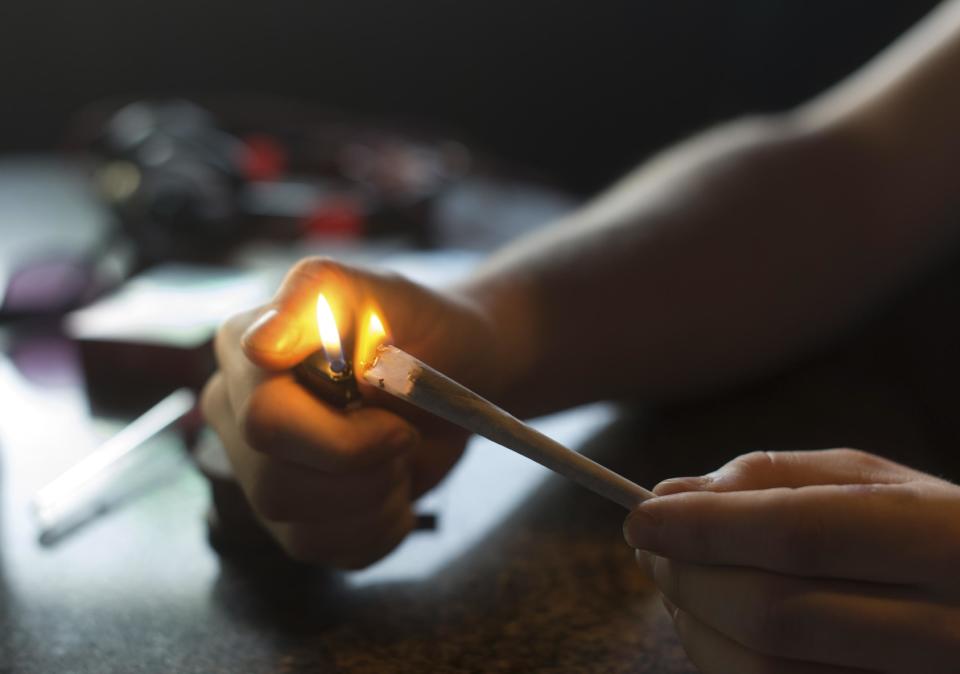 In this photo taken Friday, Dec. 20, 2013, a visitor lights a marijuana joint in coffee shop Mississippi in Maastricht, southern Netherlands. While several U.S. states have moved to legalize the sale of marijuana, the Netherlands is going in the opposite direction, clamping down on its famed tolerance policy toward weed. In Maastricht, attempts to ban foreigners from buying weed have led to a resurgence of street-dealers, while Amsterdam is shutting marijuana cafes located too close to schools. (AP Photo/Ermindo Armino)