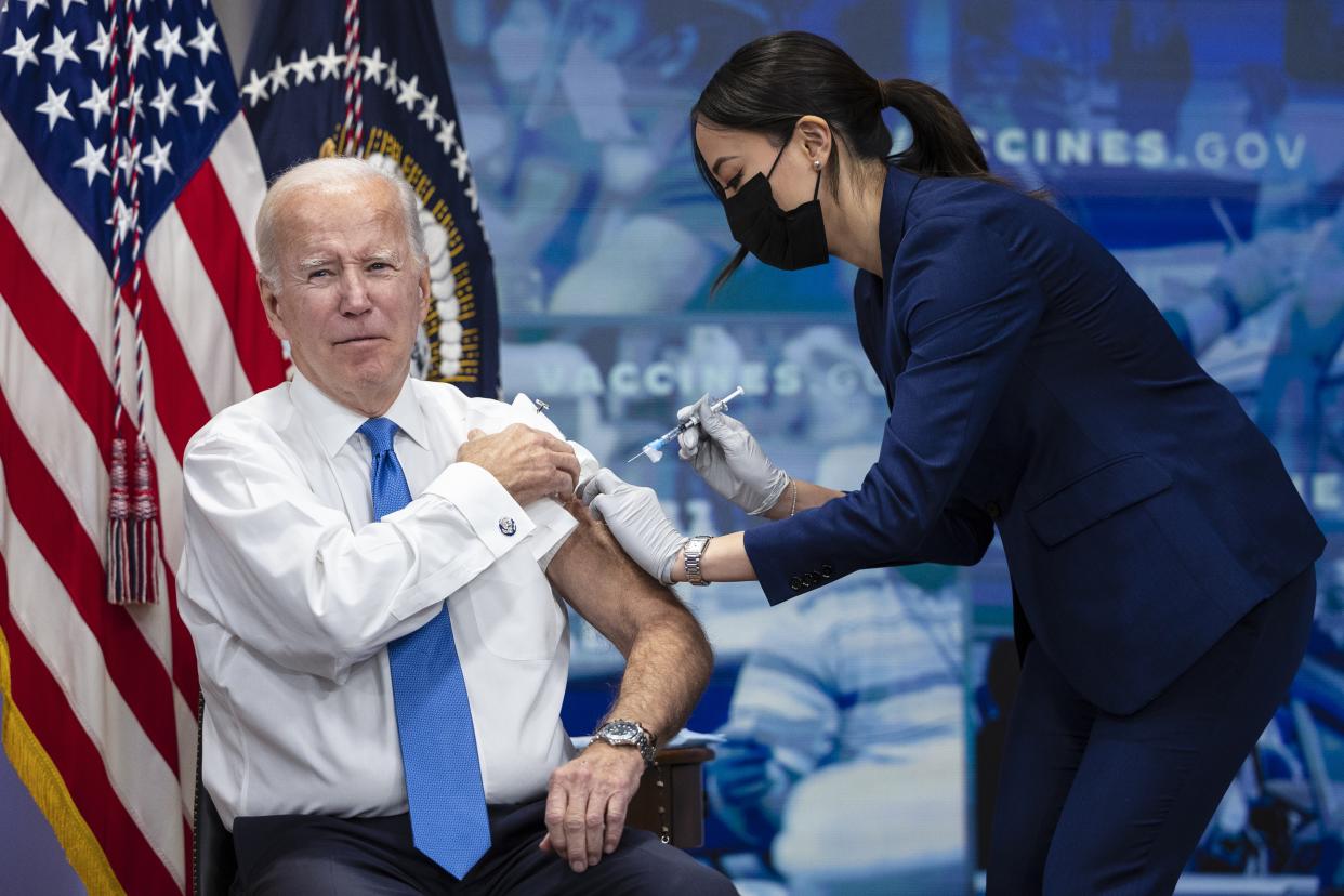 President Biden, with his sleeve rolled up, receives a COVID-19 booster shot.