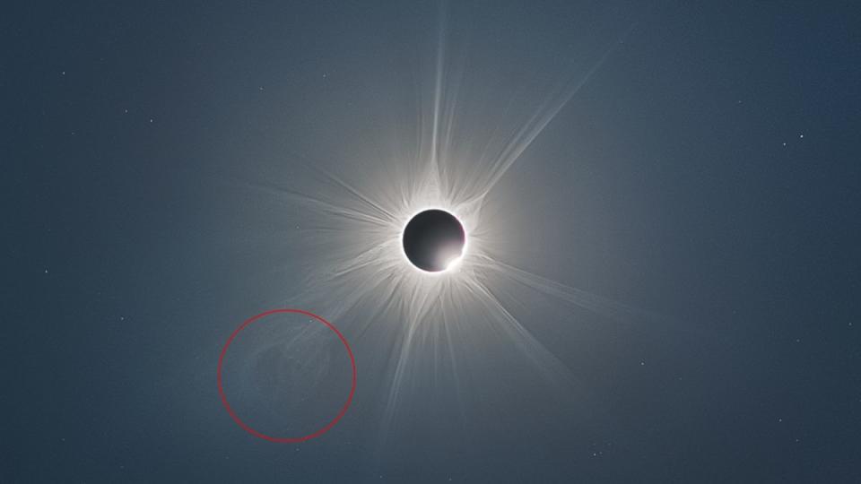 A black and white image of the sun's corona peeking out from behind the moon eclipsing the sun