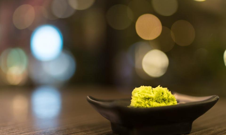 Wasabi sits in black saucer on wooden table.