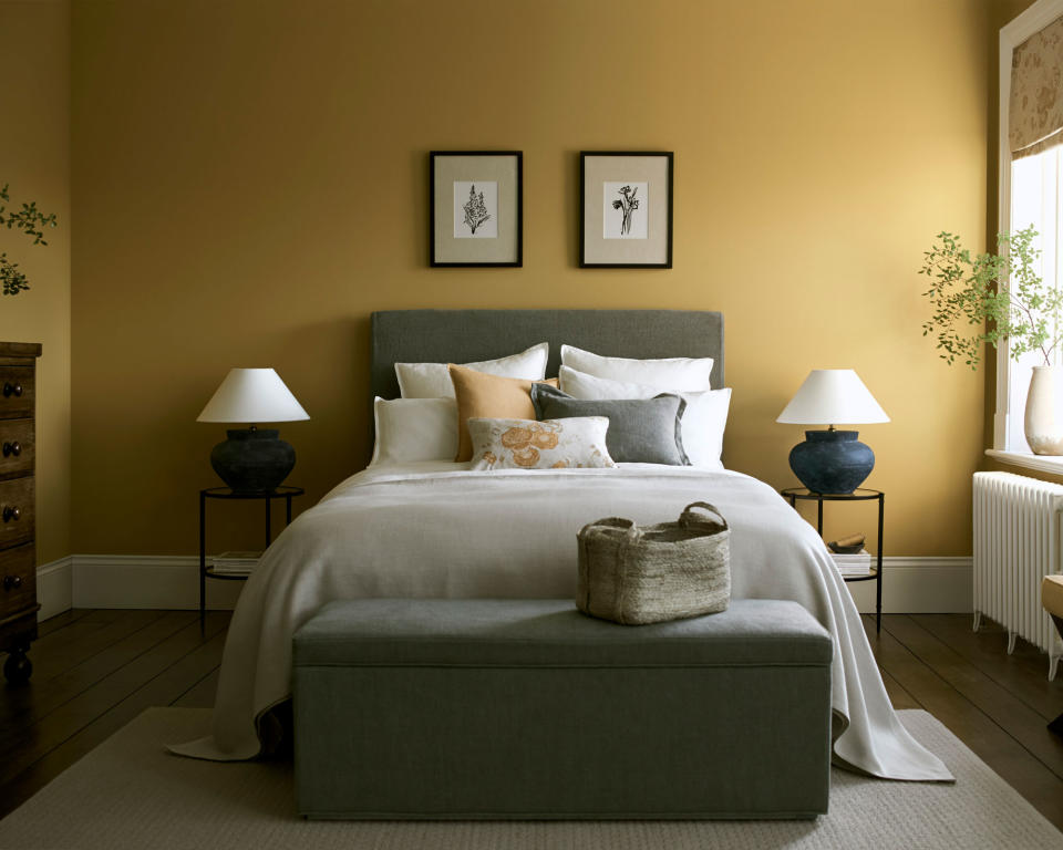 <p> In this bedroom by Neptune, painted in a gorgeous saffron yellow, the two framed floral artworks add a simple yet stylish statement above the bed.&#xA0; </p> <p> Looking to symmetry in interior design can help you decide on how and where is best to place the artwork in your bedroom. </p> <p> As shown in this space, the pretty pair of designs mirror the size of the double bed and the matching bedside tables and lamps. Creating a balanced, aesthetically pleasing design, this bedroom feels thoughtfully styled, cozy and relaxing. </p>