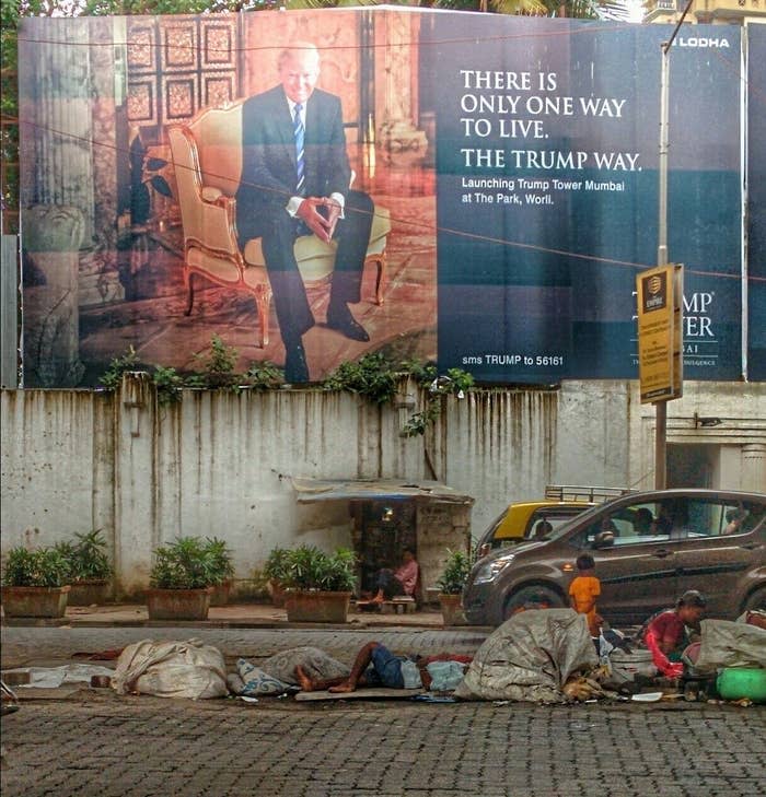 A sign for Trump saying that there is only one way to live above unhoused people in Mumbai