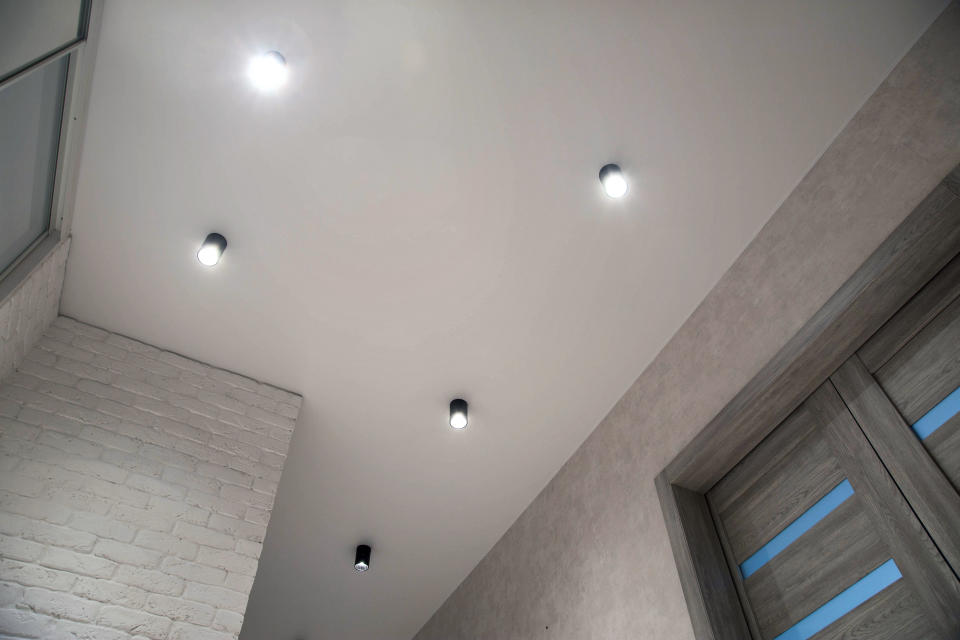 Ceiling with five recessed lights, view includes a white brick wall and a partially visible window with blinds