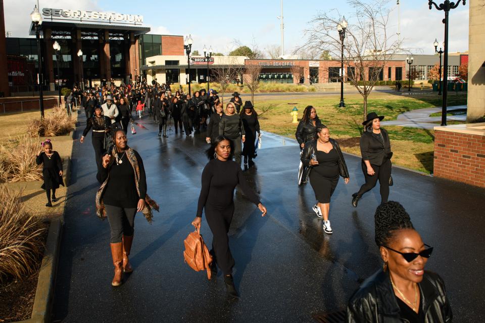 Black women walk towards the Market house for a second group portrait during the 100 Professional Black Women in Black Photo Shoot in downtown Fayetteville on Saturday, Jan. 6, 2024.