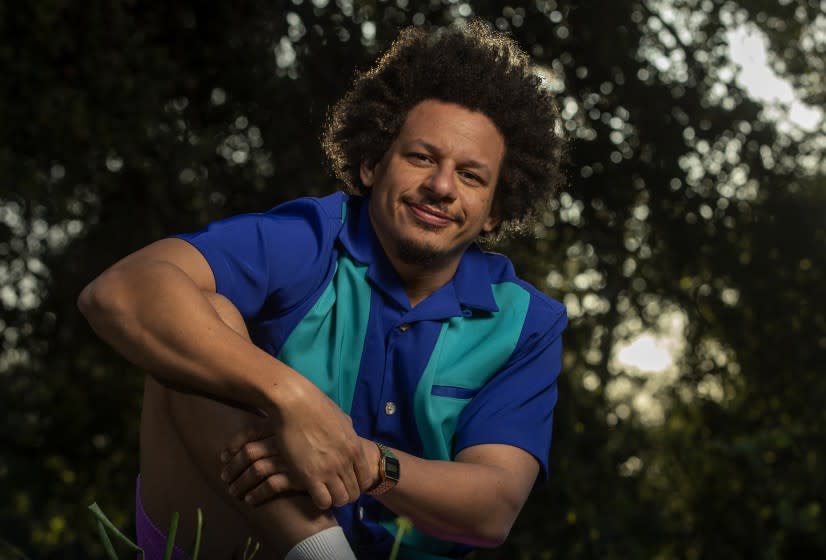 Eric Andre wearing a collared shirt posing in front of trees