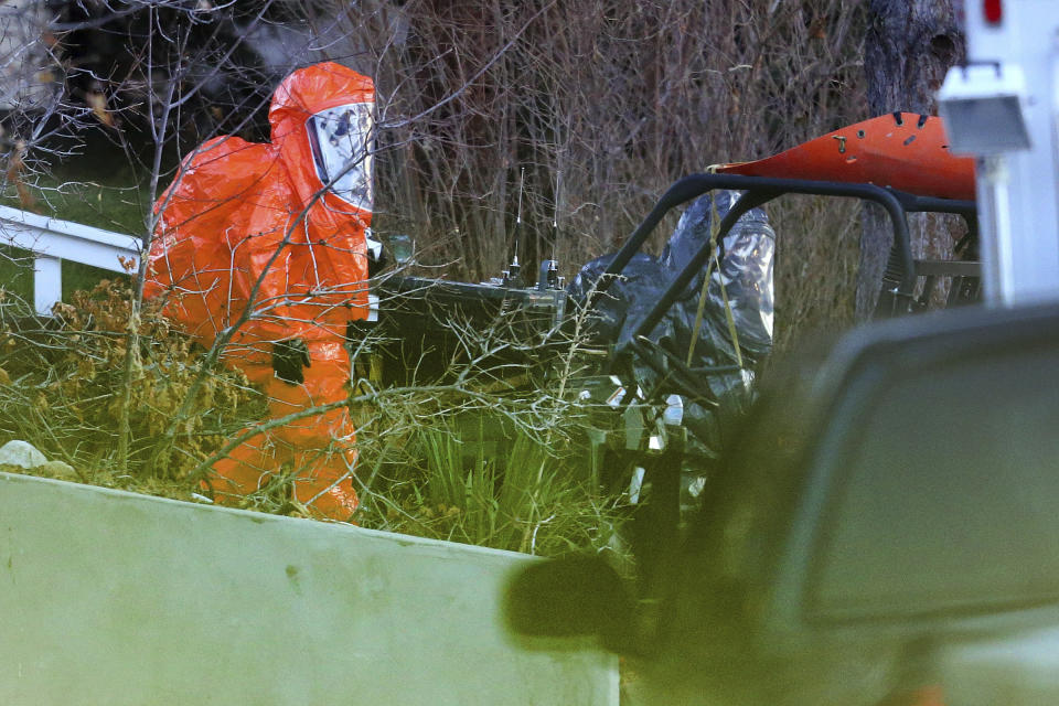 In this Nov. 22, 2016 photo, two men in protective suits exit a residence as local and federal law enforcement agencies respond to a drug bust in Cottonwood Heights, Utah. The raid on Aaron Shamo’s home in the upscale suburb of Cottonwood Heights, agents found a still-running pill press in the basement, thousands of pills and more than $1 million in cash stuffed in garbage bags, according to court documents. (Scott G Winterton/The Deseret News via AP)