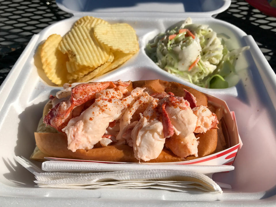 A lobster roll with potatoes and slaw