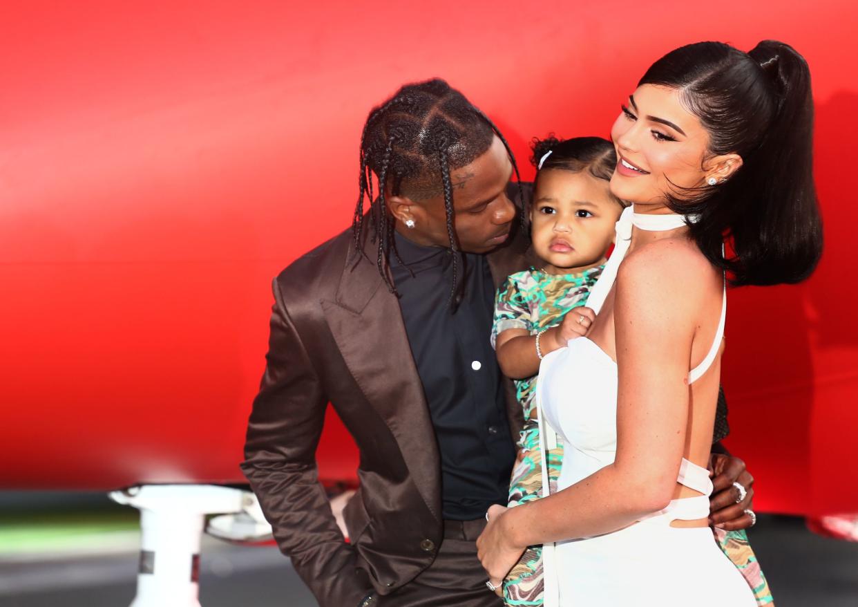 Travis Scott puts his arm around Kylie Jenner who is holding Stormi