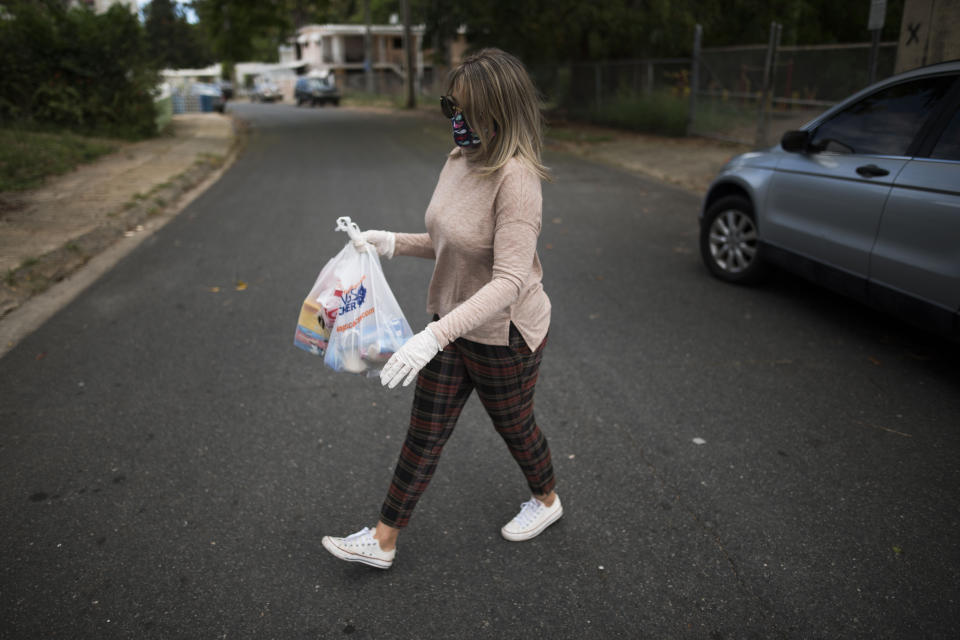 Social worker and former teacher Michelle Valentín brings food to Angel Ruiz and Ivelisse Rios, a couple that manages every day to feed their two children in the middle of the Covid-19 pandemic, in San Juan, Puerto Rico, Wednesday, April 29, 2020. Puerto Rico's government is refusing to open school cafeterias amid a coronavirus pandemic as a growing number of unemployed parents struggle to feed their children. (AP Photo/Carlos Giusti)