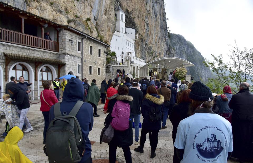 In this photo taken Tuesday, May 12, 2020, people wait in a queue in front of the Christian Orthodox monastery of Ostrog, 30 kilometers northwest of the Montenegrin capital Podgorica. Serbia has strongly protested the detention of eight Serbian Orthodox Church priests in Montenegro after thousands of people attended a religious procession despite a ban on gatherings because of the new coronavirus. Montenegrin prosecutors say that the priests are facing charges of violating health regulations during the virus outbreak by organizing the procession on Tuesday in the western town of Niksic. (AP Photo/Risto Bozovic)