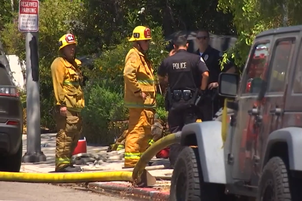 Police and firefighters investigate the scene of a car accident involving Anne Heche in Mar Vista, Calif., on Friday. (KNBC)
